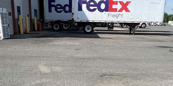 Image of Fedex truck sitting by a dumpster pad