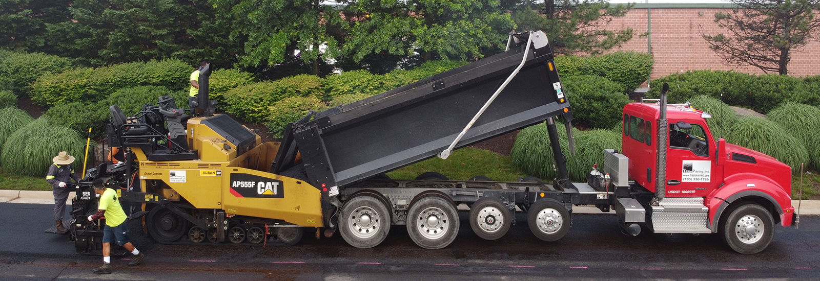 Image of dump truck pouring asphalt into a machine